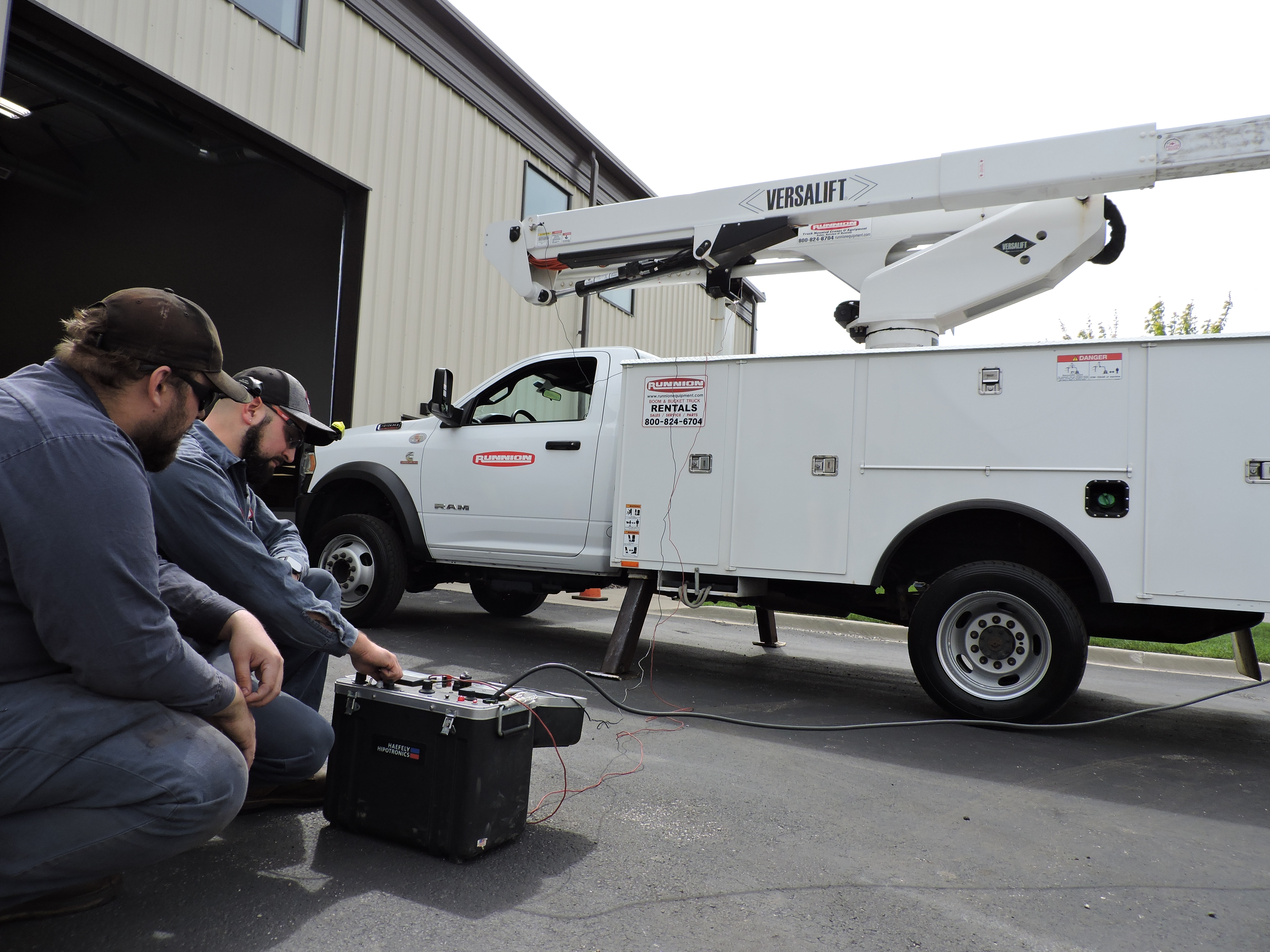 two technicians looking at a dielectric testing machine which is hooked up to a bucket truck