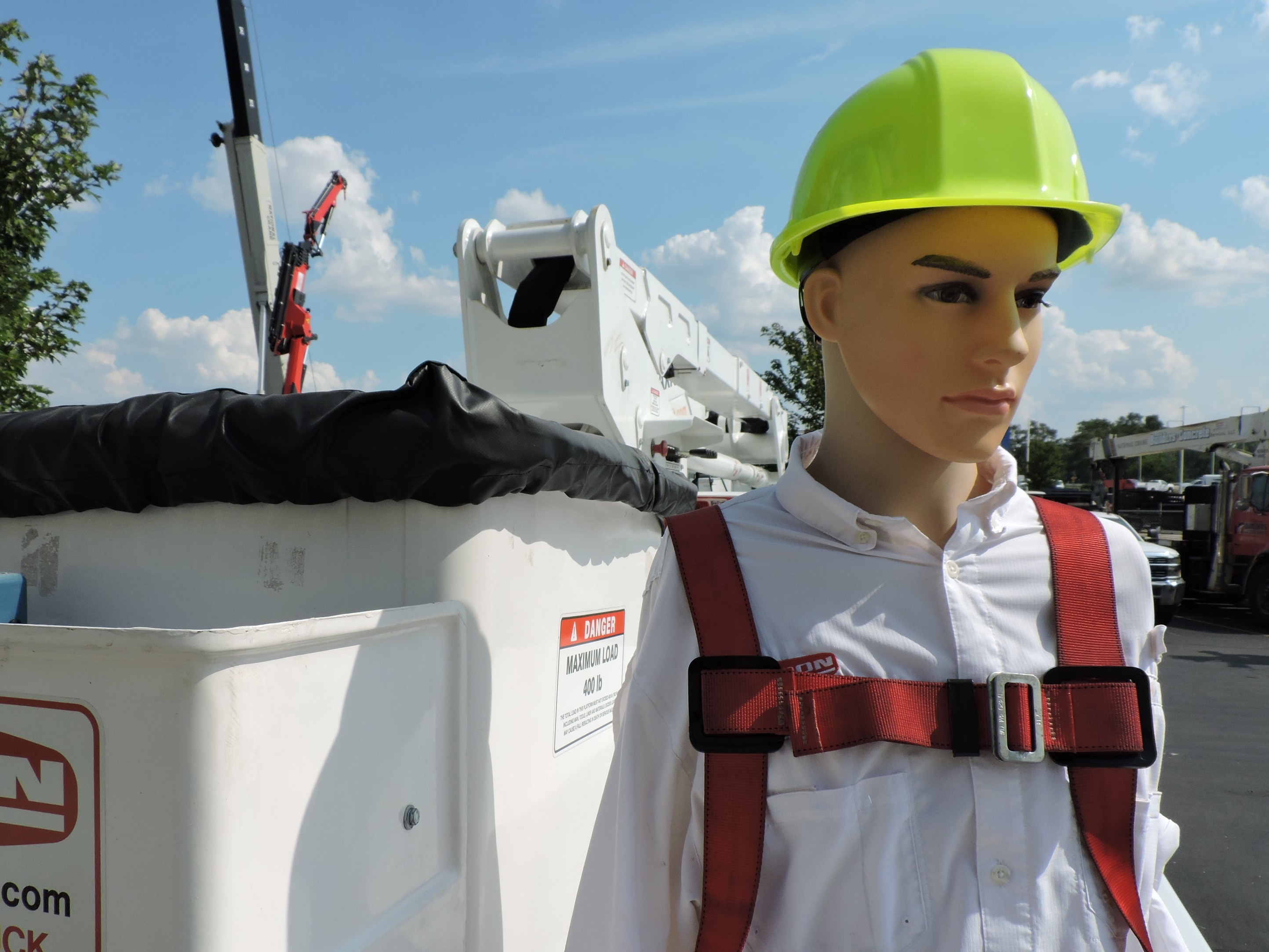 Joe the dummy in a harness and hardhat sitting next to a bucket