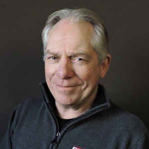 Mike Prochot smiling in a grey zip up shirt